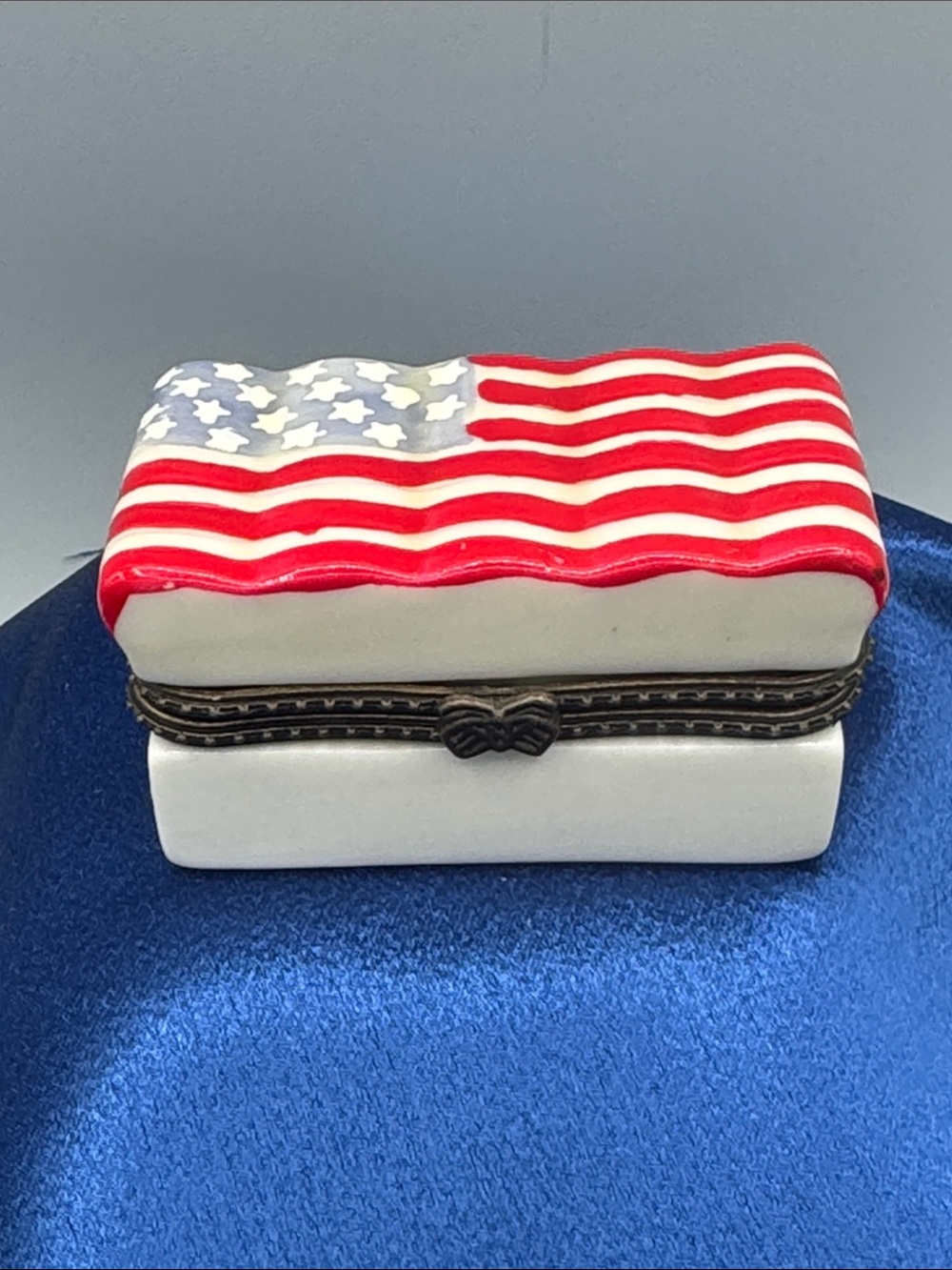 Porcelain trinket box featuring a hand-painted waving American flag on the lid.